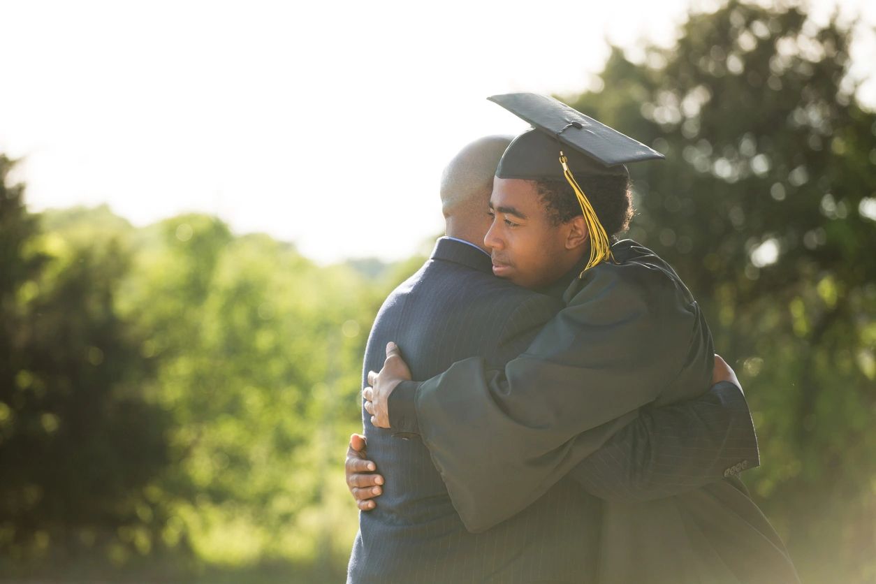 A father embracing his son at his graduation