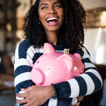 A smiling student holding a piggy bank