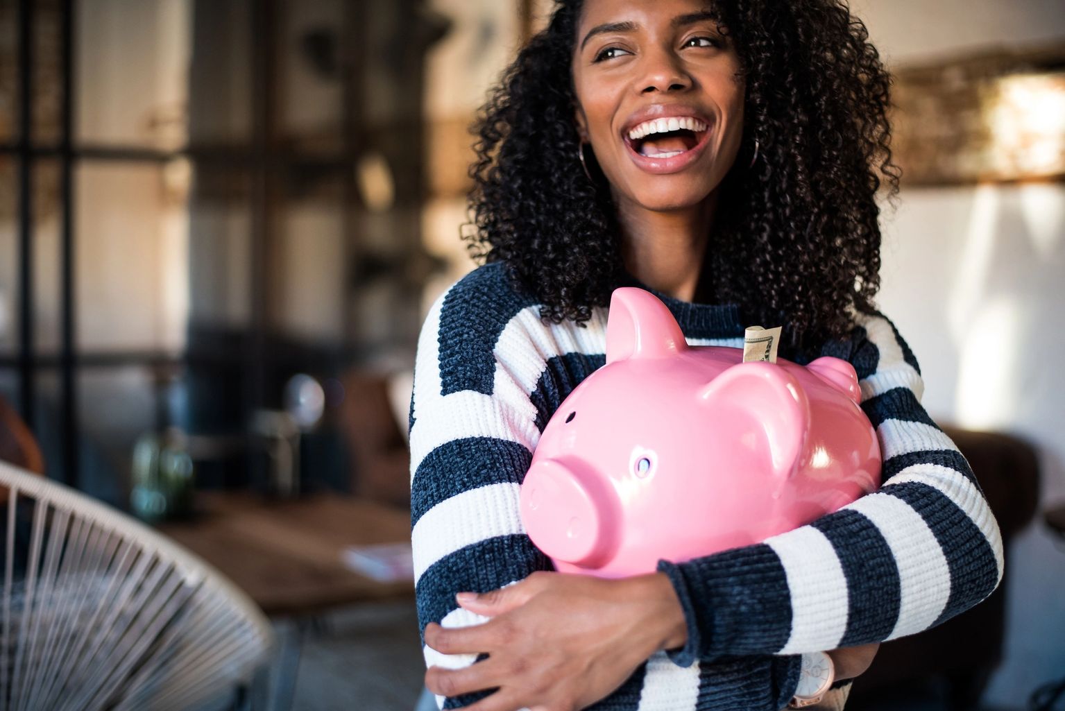 A joyful student holding a piggy bank full of savings